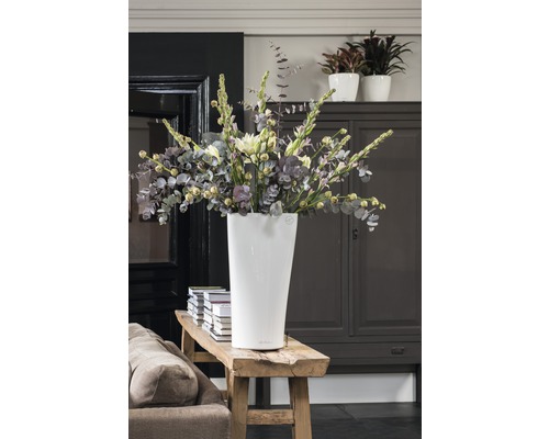 Haut vase à fleurs blanc avec bouquet sur un banc en bois dans une pièce