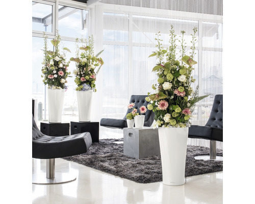 Intérieur lumineux avec arrangements floraux dans de hauts pots de fleurs, fauteuils et tapis