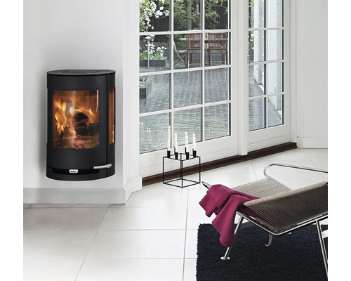 Wohnzimmer mit Kaminofen, Stuhl und Kerzenständer vor Terrassentür