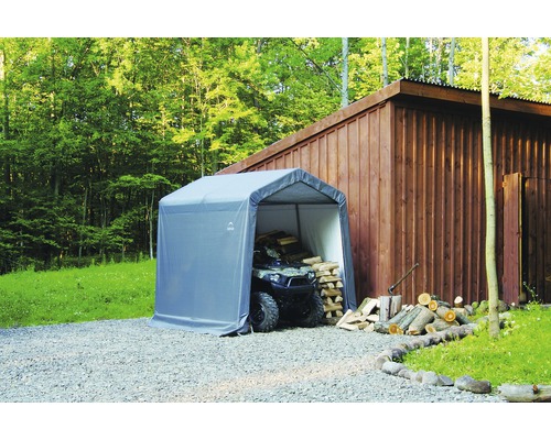 Abri avec quad et bois empilé à l''extérieur