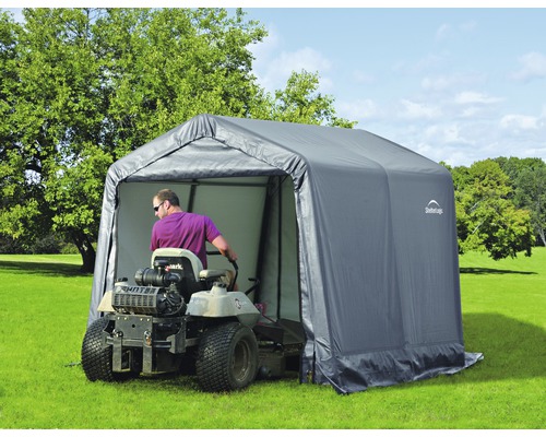 Scène de jardin avec abri pour tracteur tondeuse et tondeuse