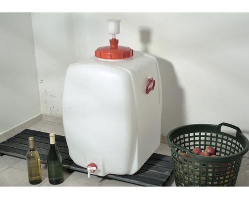 Weisser Mosttank mit Auslaufhahn, zwei Flaschen und Korb mit Früchten