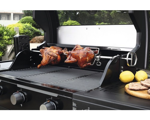 Gasgrill mit zwei Brathähnchen auf einem Drehspiess und Zitronen auf einem Holzbrett