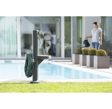 Scène de jardin avec borne fontaine, tuyau d''arrosage et femme avec arrosoir