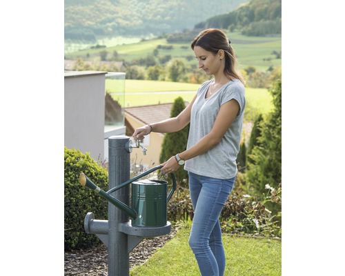 Femme remplissant un arrosoir à un robinet de jardin