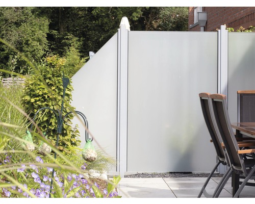 Gartenszene mit Sichtschutzelement, Tisch und Stühlen auf einer Terrasse.