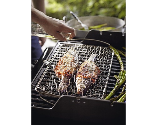 Deux poissons et asperges vertes sur un gril avec une personne versant de l''huile dessus