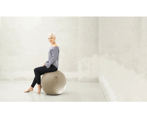 Frau sitzt auf einem Gymnastikball in einem hellen Raum.