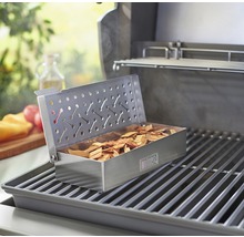 Barbecue avec boîte à fumer remplie de bois à fumer sur une grille de cuisson
