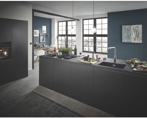 Cuisine lumineuse et spacieuse avec îlot de cuisine, évier et coin repas en arrière-plan.