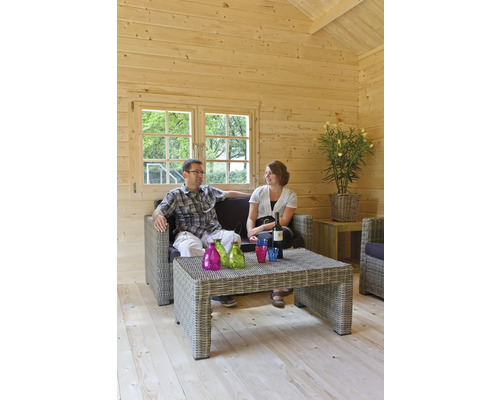 Petite maison en bois clair avec un couple sur un canapé en rotin avec table, bouteilles et verres