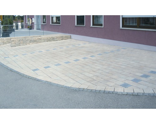 Zone pavée devant un bâtiment avec mur en pierre