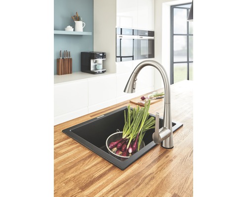 Évier de cuisine avec robinet et légumes sur un plan de travail en bois