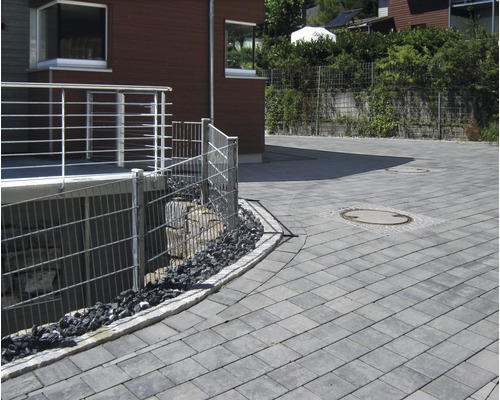 Espace extérieur avec pavés, clôture métallique et maison