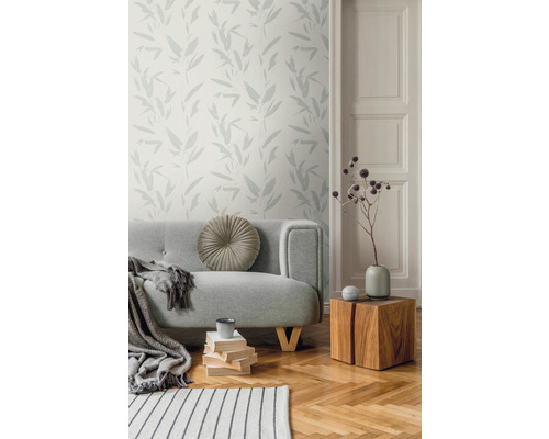 Salon avec canapé gris, table en bois et papier peint à motifs végétaux