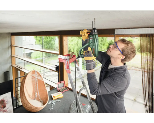 Handwerker bohrt mit einer Bohrmaschine in die Decke eines Raumes.