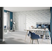 Helles Schlafzimmer mit Bett, Schreibtisch und Backsteinwand