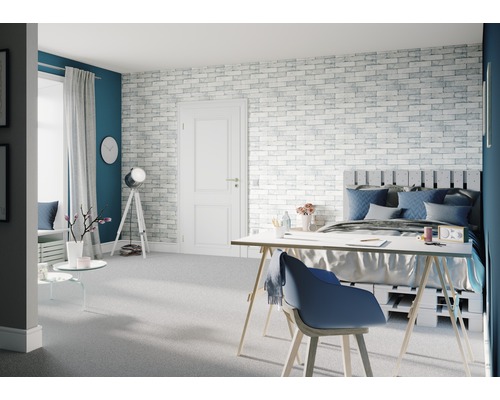 Helles Schlafzimmer mit Bett, Schreibtisch und Backsteinwand