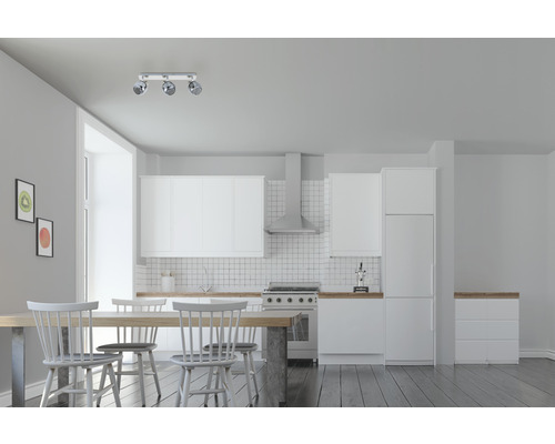 Pièce lumineuse avec kitchenette, table à manger et plafonnier à trois spots.