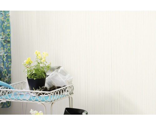 Mur clair avec une structure verticale à côté d''une table avec des fleurs