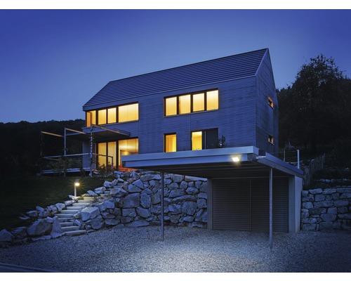 Maison moderne avec abri de voiture, escalier en pierre et éclairage de jardin le soir