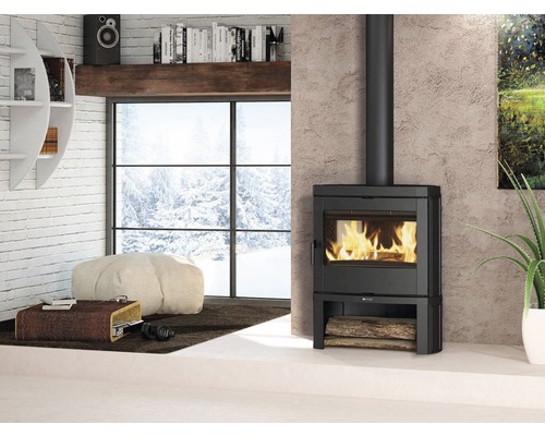 Salon avec poêle à bois, pouf et vue sur paysage enneigé