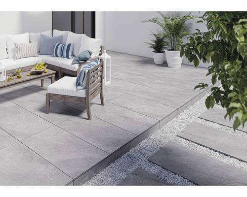 Terrasse avec des carreaux gris, des meubles de jardin et des plantes.