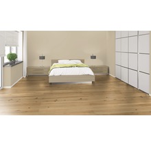 Helles Schlafzimmer mit Holzboden, Doppelbett, Nachttischen, Lampen, Vorhängen und Schrank.