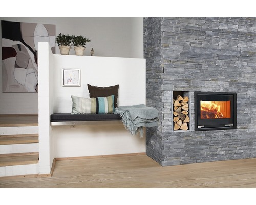 Salon avec mur en pierre, cheminée, bûches et banc