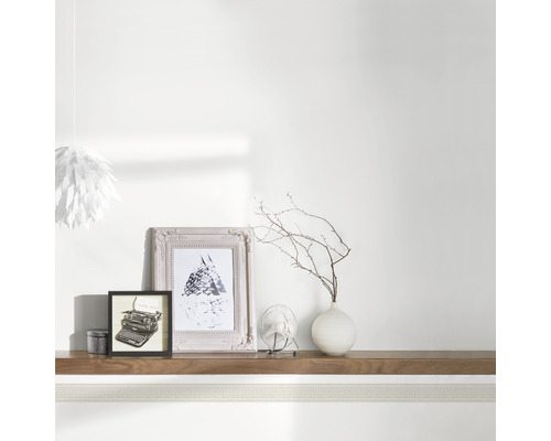 Dekorative Bordüre im Zimmer mit Fotorahmen, Vase und Lampe.