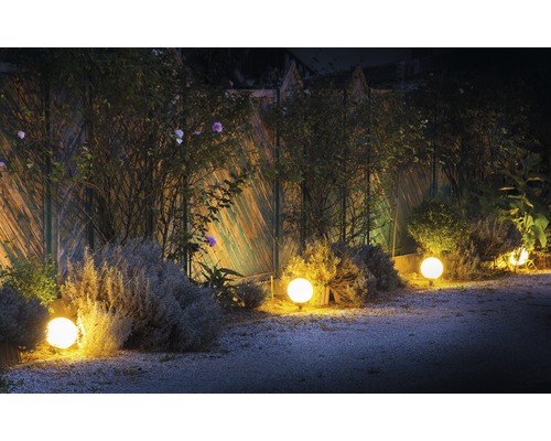 Gartenbeleuchtung mit mehreren kugelförmigen Leuchten entlang eines Zauns