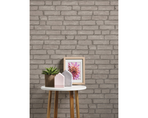 Pièce avec papier peint à motif brique, table, plante et cadre photo.