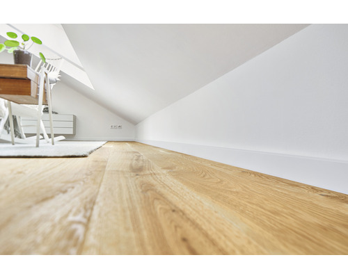 Chambre mansardée avec parquet, murs blancs et meubles