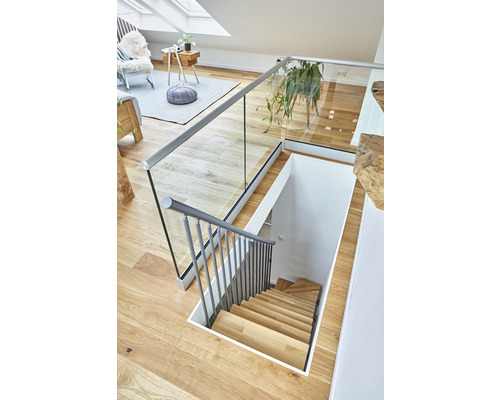 Vue intérieure d''une maison avec un escalier en bois, une balustrade en verre et un intérieur lumineux.
