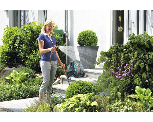 Femme arrose le jardin avec un dévidoir
