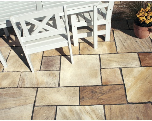 Dallage en pierre naturelle posé à l''extérieur avec coin salon et pot de fleurs.