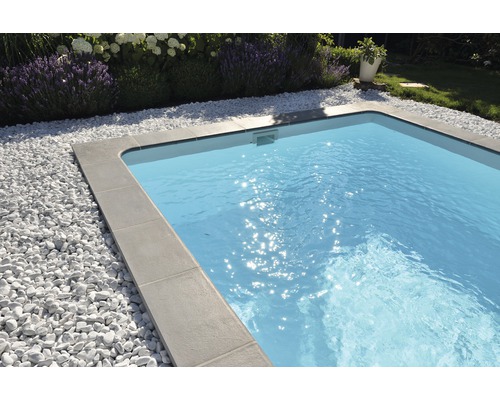 Piscine avec margelles grises et gravier décoratif blanc dans le jardin