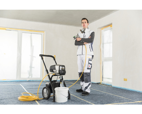 Homme avec un pulvérisateur de peinture dans une pièce.