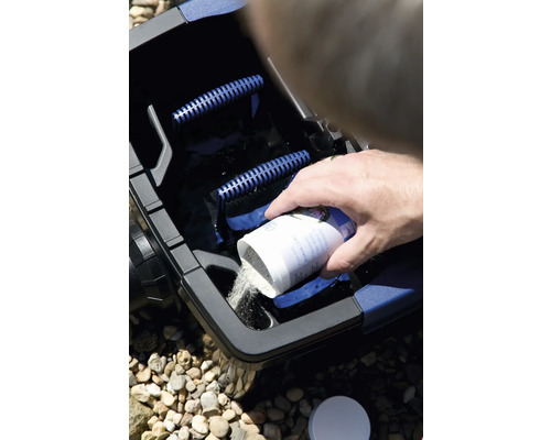 Une personne verse un produit d''entretien de bassin dans un filtre de bassin.