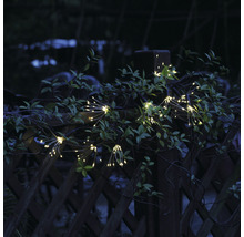 Guirlande lumineuse scintillante avec des bouquets fixés à une clôture de jardin.