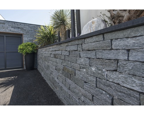 Aussenbereich mit einer Mauer aus Naturstein und dekorativen Pflanzen
