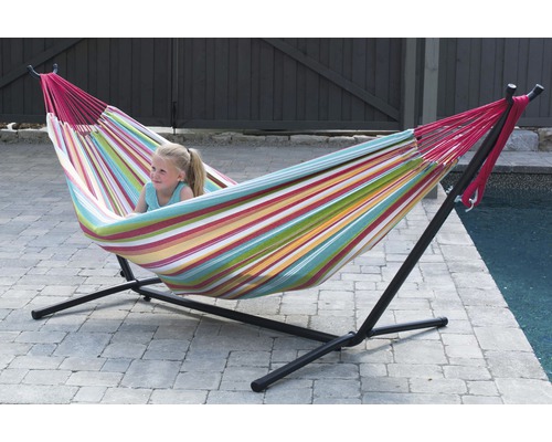 Fille se détend dans un hamac rayé avec un cadre en métal noir dans le jardin