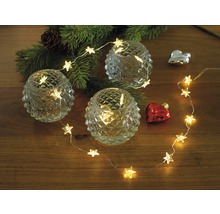 Arrangement décoratif avec photophores, guirlande lumineuse en forme d''étoile et décorations de Noël sur une table.