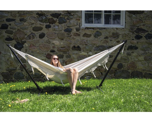 Femme se détend dans un hamac avec support dans le jardin.