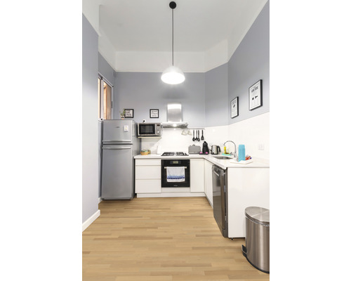 Cuisine claire avec appareils, armoires et plancher en bois.