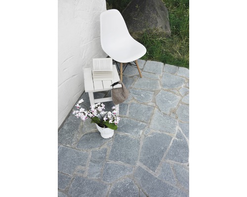 Aménagement de terrasse avec dalles en pierre naturelle, chaise et table d''appoint
