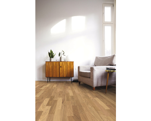 Espace de vie lumineux avec plancher en bois, fauteuil et commode