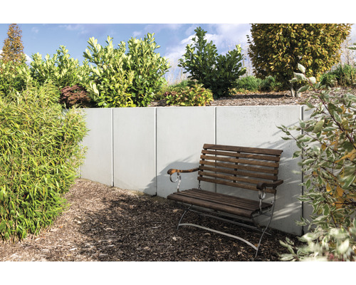 Scène de jardin avec mur en béton, talus planté et banc en bois