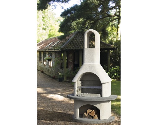 Photo extérieure d''un four à barbecue en pierre avec rangement pour le bois et grille devant un pavillon de jardin