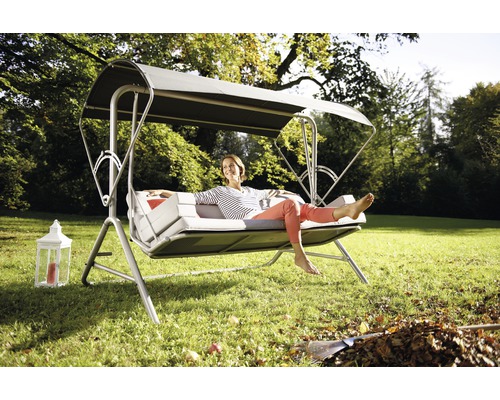 Gartenschaukel mit Dach und liegender Person im Garten